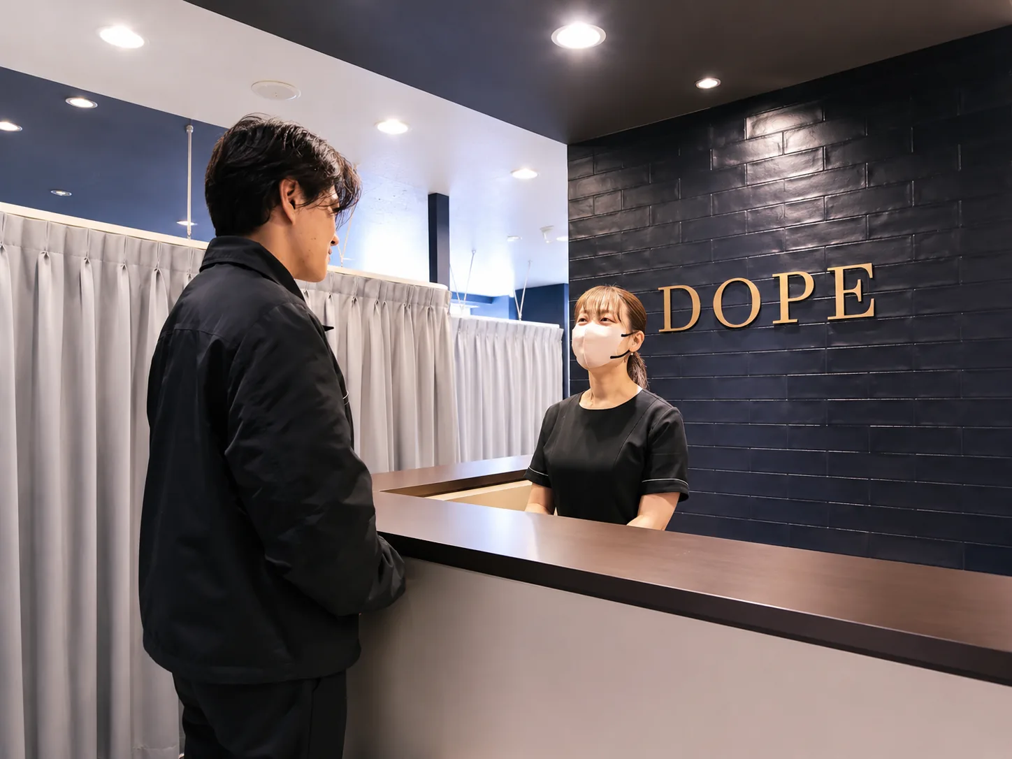 メンズ眉毛サロン DOPE の受付で接客するスタッフ