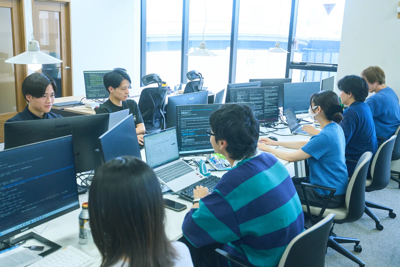 坂下淳一を含むメンバーがオフィスで業務に取り組む様子