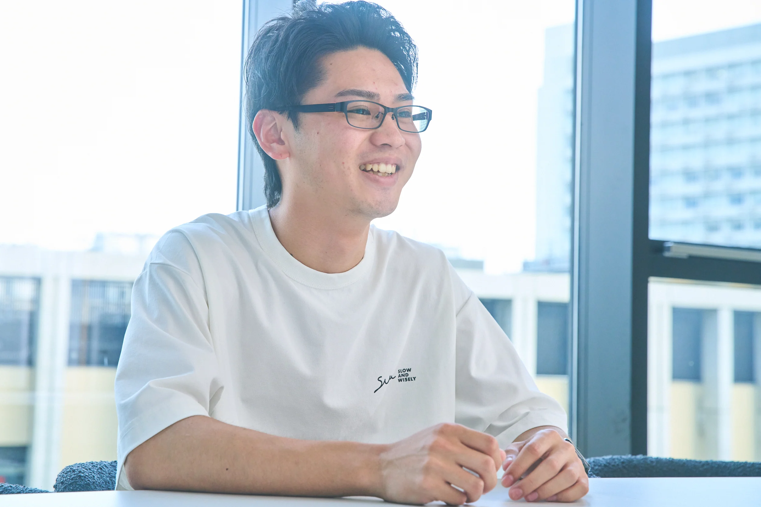 窓際で前職からの転職理由を語る鈴木貴登