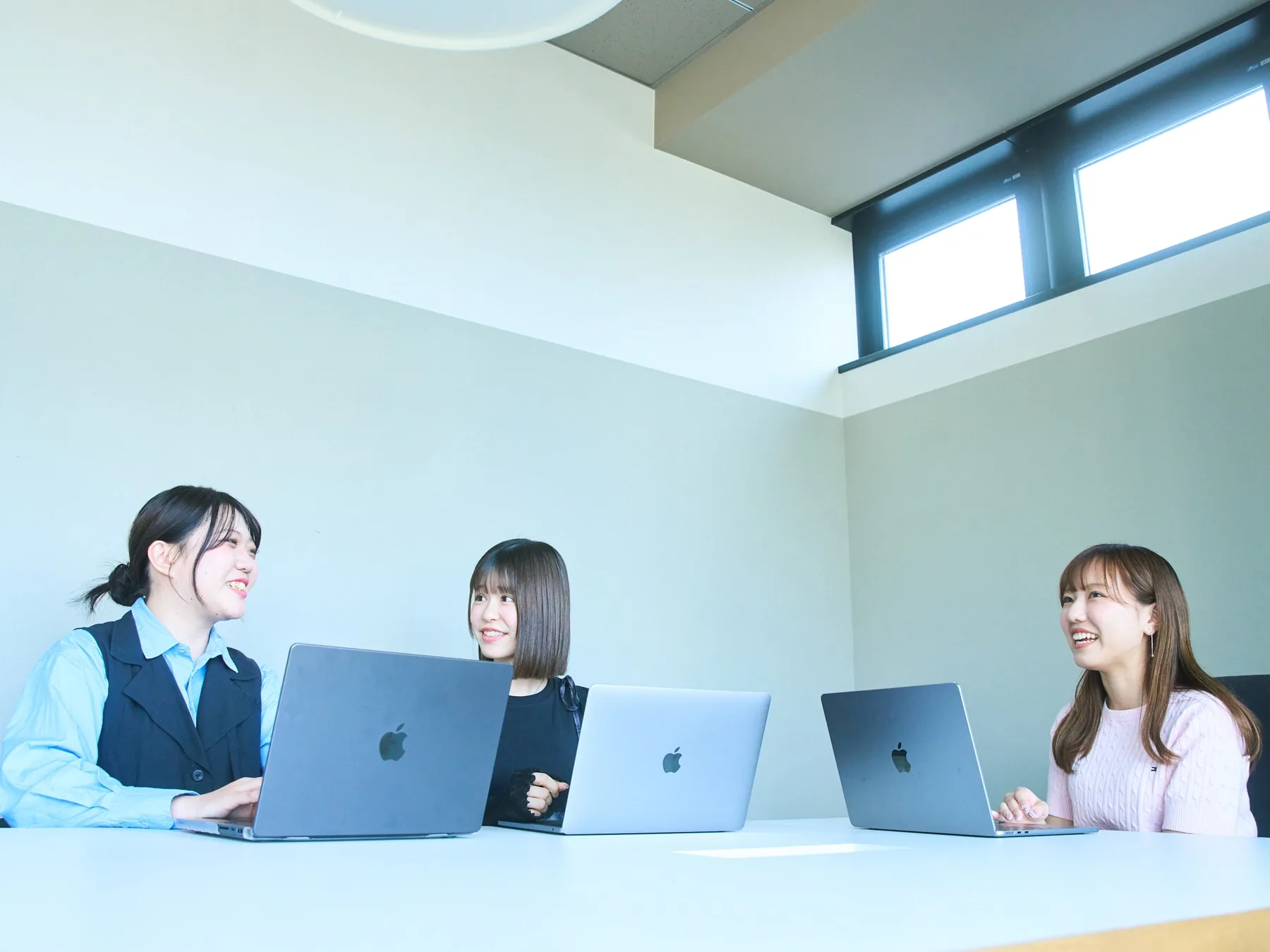 ノートパソコンを囲んで施策を話し合うWebマーケティングチーム