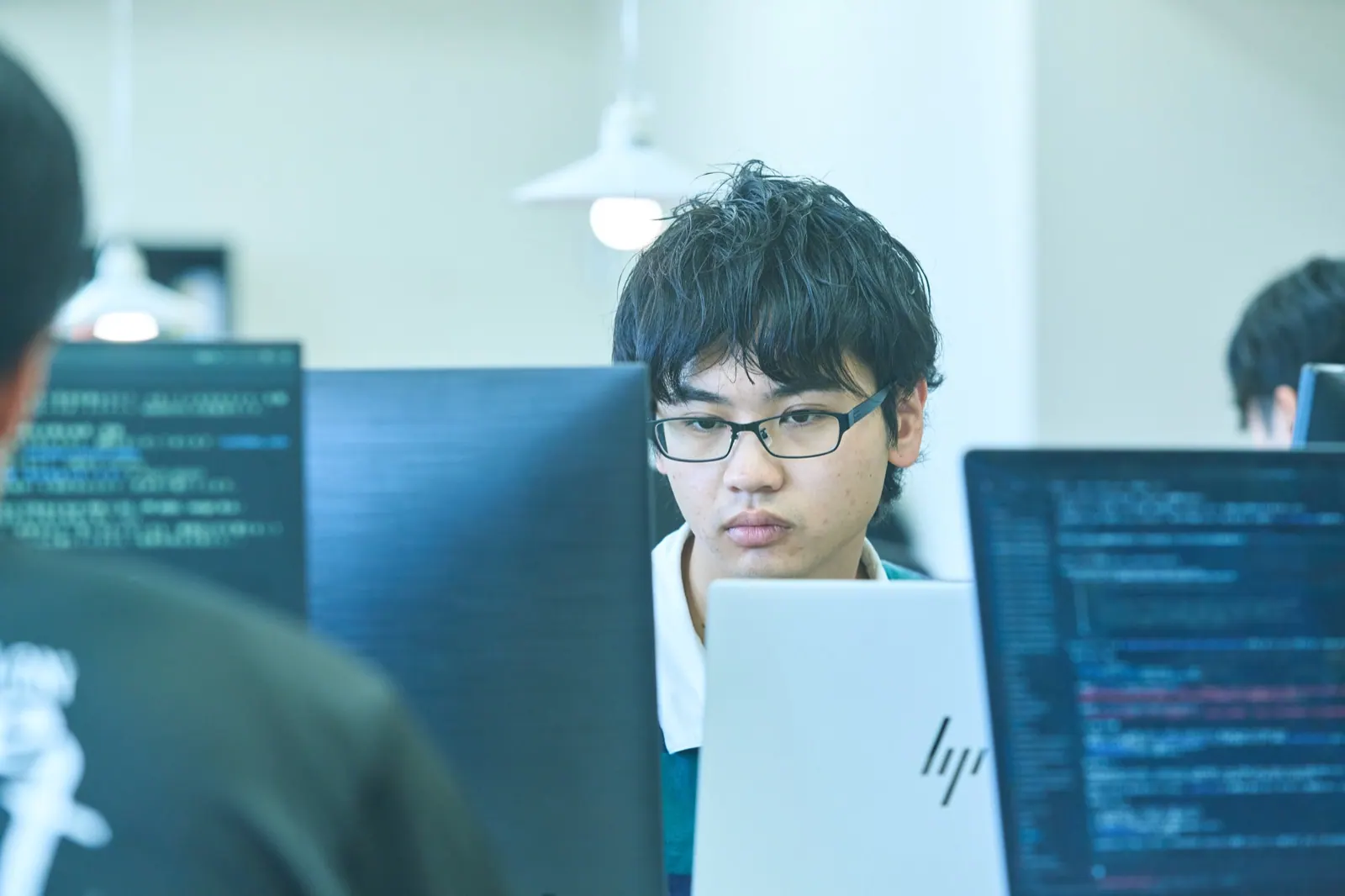 コードが表示された画面に囲まれて分析業務を進めるプロパゲートのメンバー